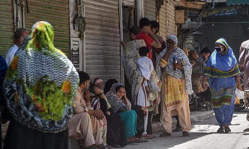 People gather as they wait for the reopening of shops in Lahore on Saturday. — AFP